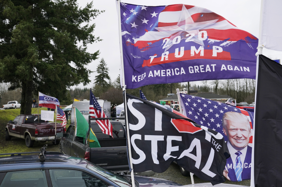FILE - Flags supporting President Donald Trump and one that reads "Stop the Steal" are displayed during a protest rally, Jan. 4, 2021, at the Farm Boy Drive-In restaurant near Olympia, Wash. A review by The Associated Press in the six battleground states disputed by former President Trump has found fewer than 475 cases of potential voter fraud, a minuscule number that would have made no difference in the 2020 presidential election. Democrat Joe Biden won Arizona, Georgia, Michigan, Nevada, Pennsylvania and Wisconsin and their 79 Electoral College votes by a combined 311,257 votes out of 25.5 million ballots cast for president. (AP Photo/Ted S.
