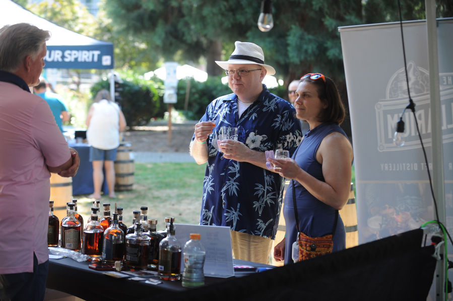 Allen and Sarah Green of Vancouver sample craft whiskey and brandy at The Distillarium booth while owner Kenny Miller, left, explains how the fine spirits are made at his Yakima distillery Saturday at the Craft Beer and Wine Fest at Esther Short Park in downtown Vancouver.