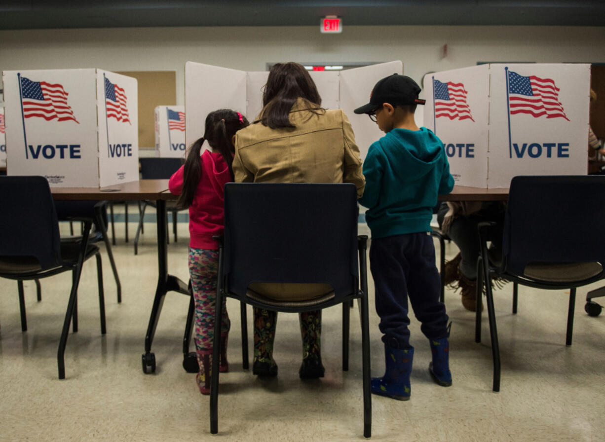 A woman and her children vote at a polling station during the mid-term elections at the Fairfax County bus garage in Lorton, Virginia. on Nov. 6, 2018.