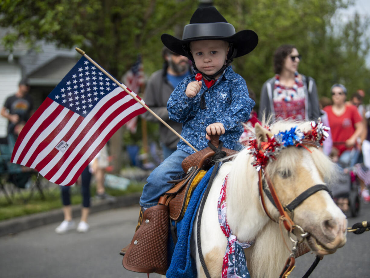 Two-year-old Jack Bononcini holds an American flag and rides a pony named Buttercup during downtown Ridgefield's Fourth of July parade.