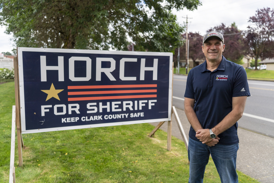 Clark County sheriff candidate John Horch stands next to a campaign sign on Northwest 139th Street in Salmon Creek.