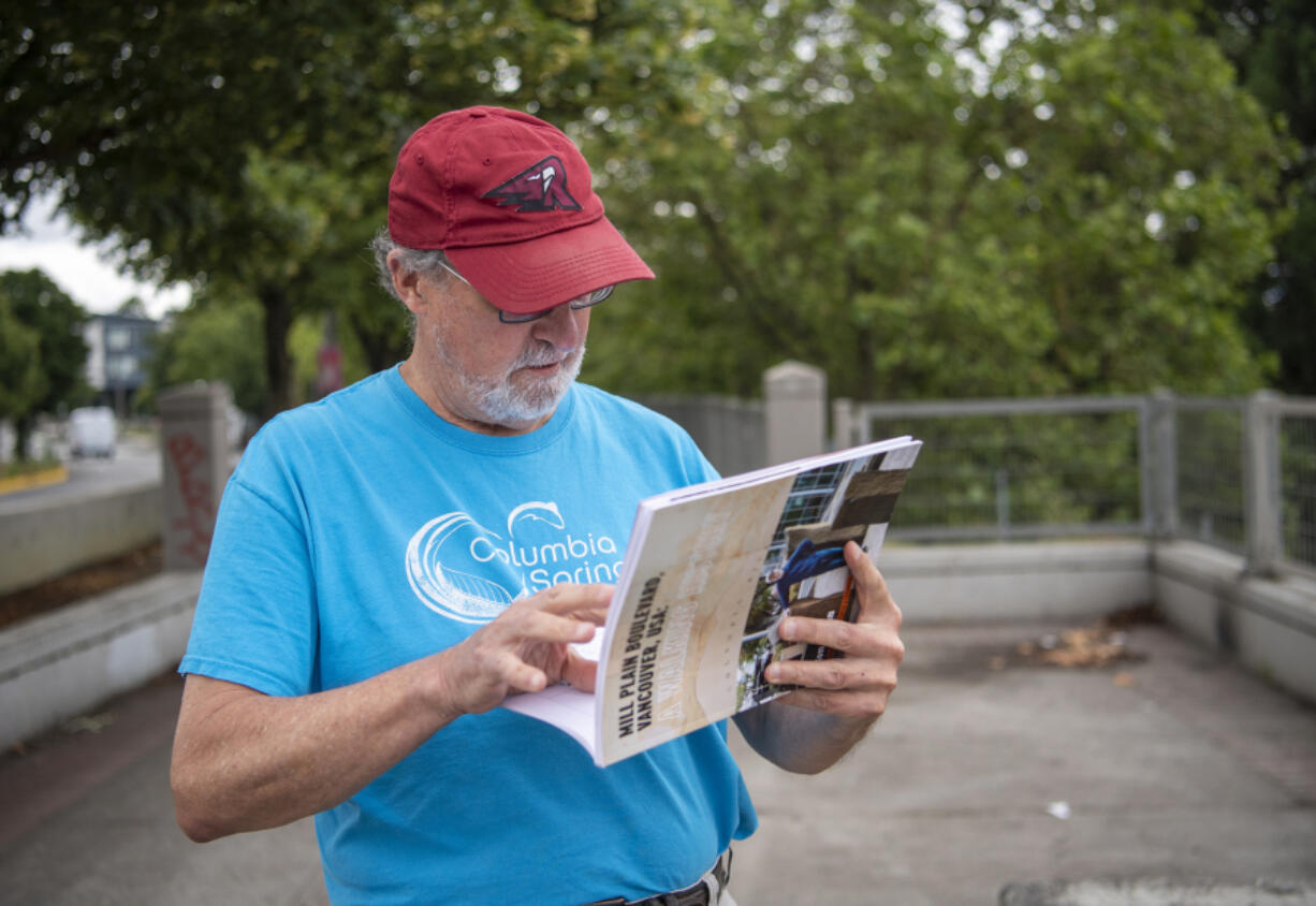 Tom Lineham double checks a map in his book, "Mill Plain Boulevard, Vancouver, USA: A Walking History," while strolling along the street on a recent morning.