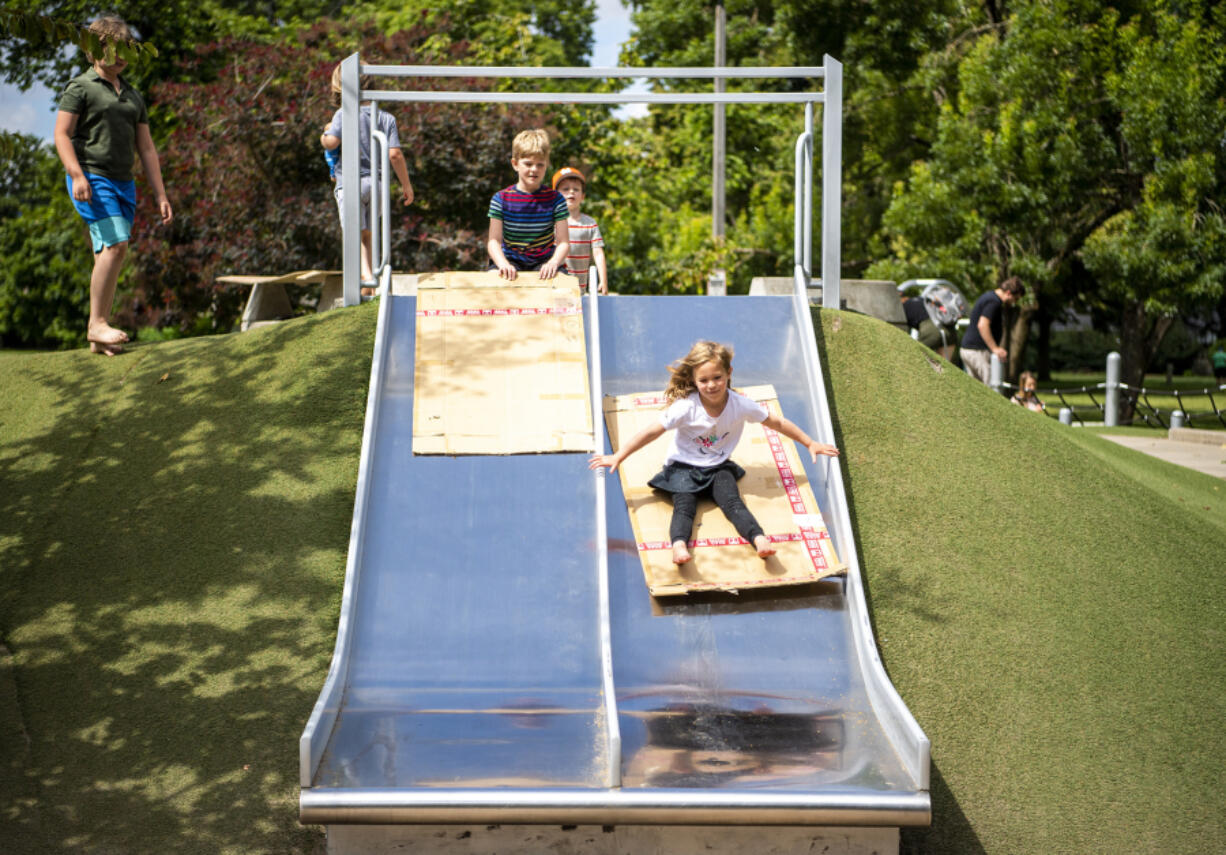 Miles Buttrill, 9, left, watches his sister Lillian Buttrill slides down a slide at Arbor Lodge Park in Portland. A Harper's Playground is being installed at Marshall Park in Vancouver. The playground is designed to be accessible and usable by all children, including those experiencing disabilities.
