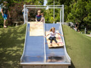 Miles Buttrill, 9, left, watches his sister Lillian Buttrill slides down a slide at Arbor Lodge Park in Portland. A Harper's Playground is being installed at Marshall Park in Vancouver. The playground is designed to be accessible and usable by all children, including those experiencing disabilities.