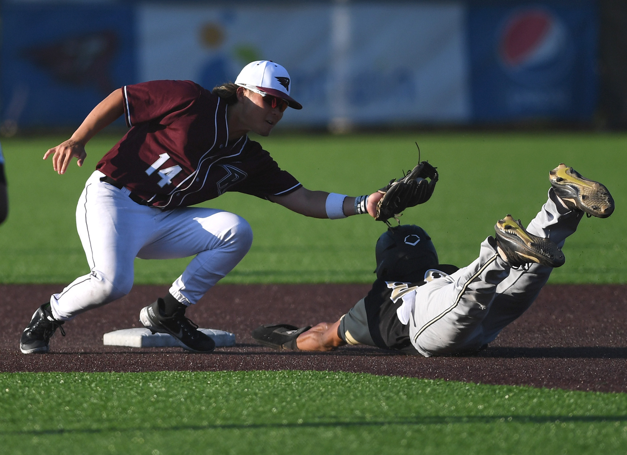 Raptors infielder Jake Tsukada, left, tags out a Bend baserunner Tuesday, July 26, 2022, during a game between Ridgefield and the Bend Elks at the Ridgefield Outdoor Recreation Complex.