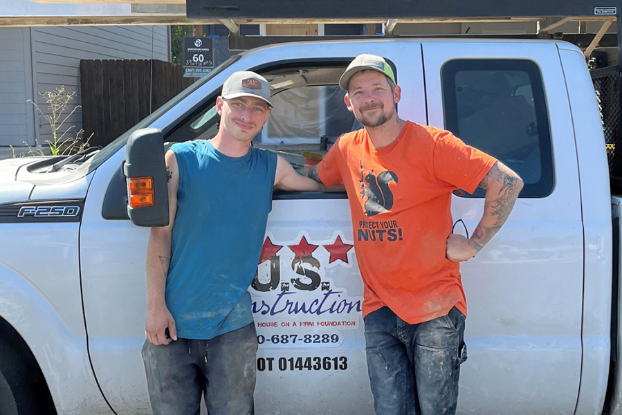 Corbin Cavagna, left, and Timothy Ward pose with their U.S. Construction truck. On their way to a job site Thursday morning, they spotted a house fire in the Barberton area and helped rescue an 11-year-old girl from inside.