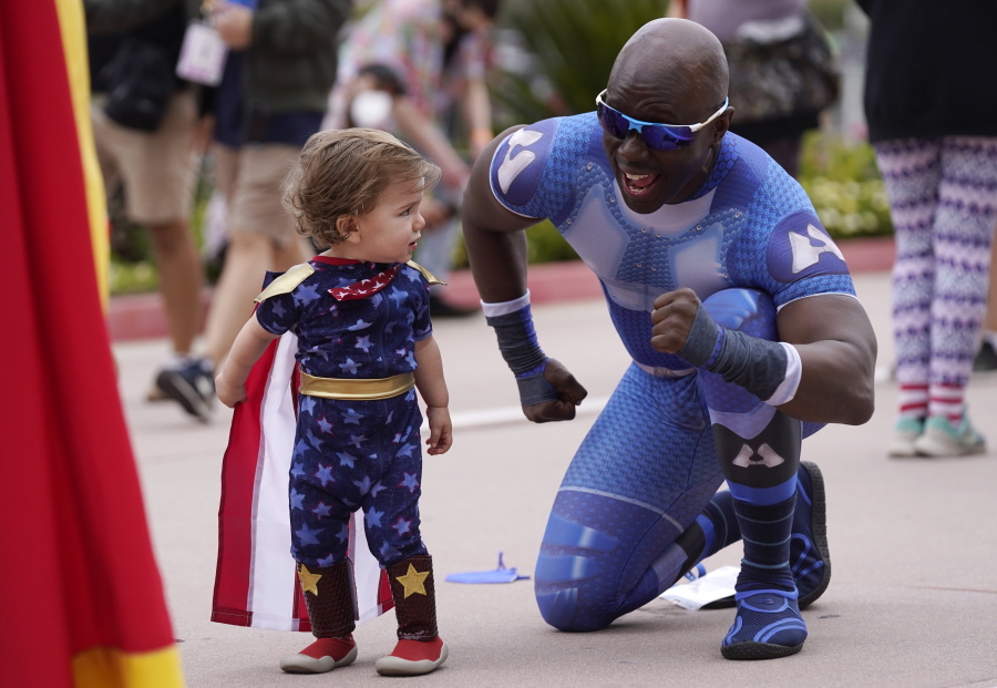 Jay Acey, right, dressed as A-Train from the television series "The Boys," mingles with Maddox Cruz, 1, of Orange, Calif., outside Preview Night at the 2022 Comic-Con International at the San Diego Convention Center, Wednesday, July 20, 2022, in San Diego.