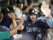 Seattle Mariners' Cal Raleigh is greeted in the dugout after he hit a solo home run against the Texas Rangers during the seventh inning of a baseball game, Tuesday, July 26, 2022, in Seattle. (AP Photo/Ted S.