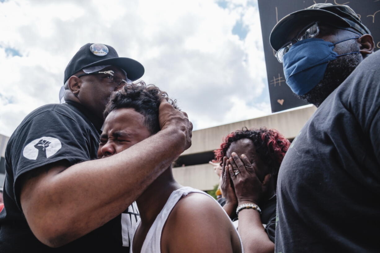 Javon Williams, 13, is comforted by Rev. Jaland Finney, left, as he speaks during a march and rally for Jayland Walker, Sunday, July 3, 2022, in Akron, Ohio. Also pictured at center right is Lanette Williams, reacting after Javon's speech. Williams had just viewed the video released by police detailing the shooting death of Walker.