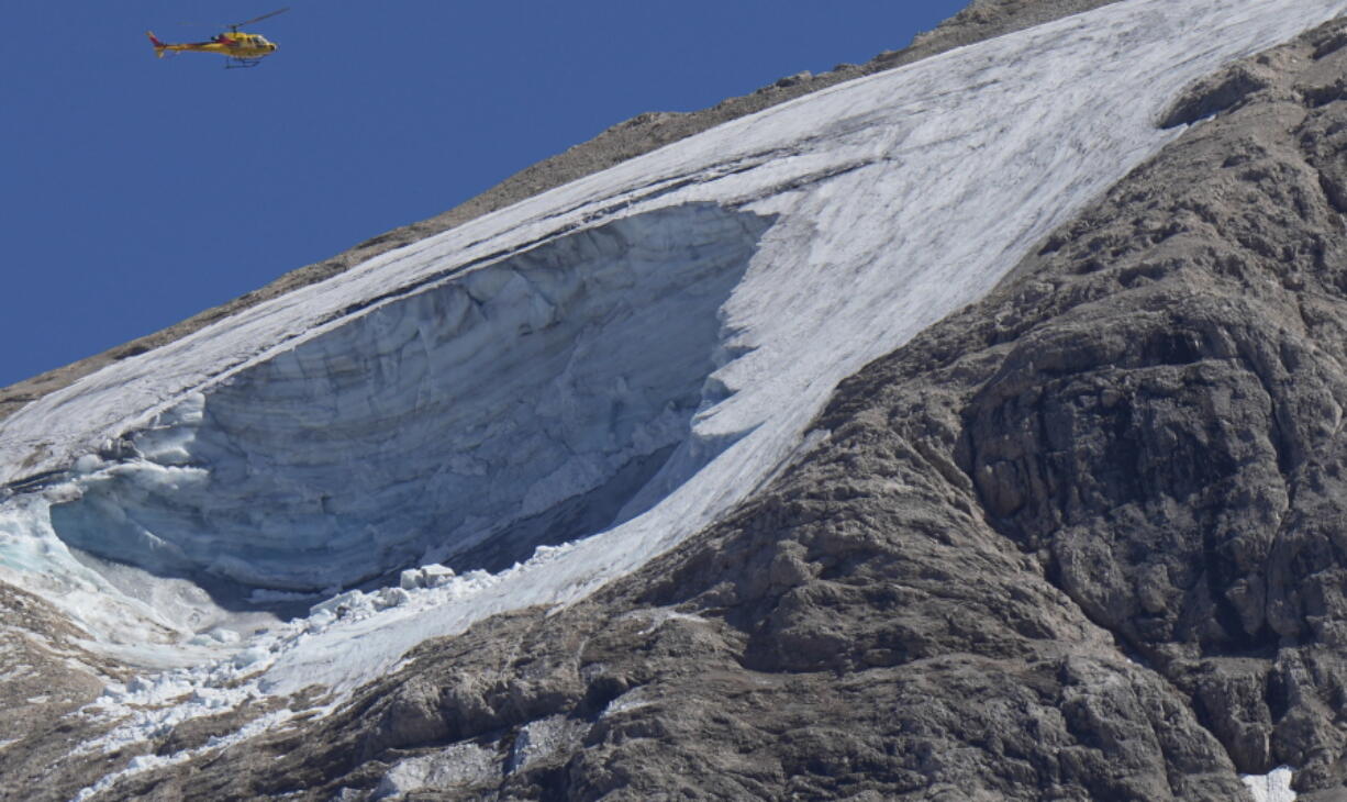 A rescue helicopter hovers Monday over the Punta Rocca glacier near Canazei, in the Italian Alps in northern Italy, a day after a huge chunk of the glacier broke loose, sending an avalanche of ice, snow and rocks onto hikers.