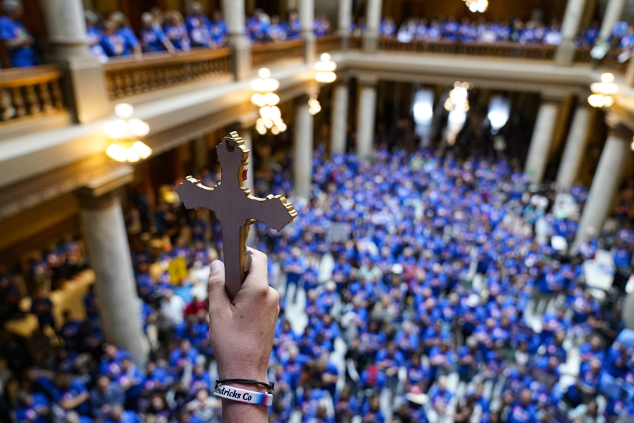 FILE - Luke Howard, of Avon, Ind., holds a crucifix aloft as anti-abortion supporters rally as the Indiana Senate Rules Committee met a Republican proposal to ban nearly all abortions in the state during a hearing at the Statehouse in Indianapolis, July 26, 2022.