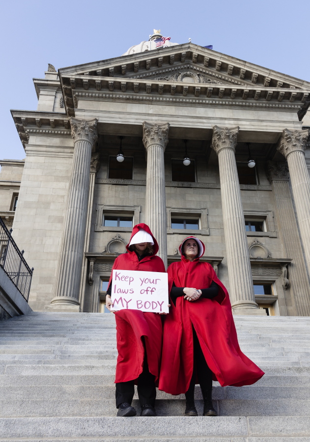 FILE - Two people stand on the steps of the Idaho State Capitol Building,   during a protest, in downtown Boise, Idaho on May 3, 2022. The U.S. Supreme Court's ruling overturning Roe v. Wade has attorneys, prosecutors and residents of red states facing a legal morass created by decades of anti-abortion legislative efforts. (Sarah A.
