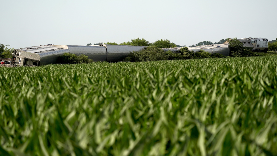 An Amtrak train which derailed after striking a dump truck is seen beyond a corn field Monday, June 27, 2022, near Mendon, Mo.