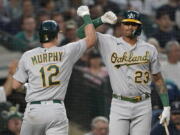 Oakland Athletics' Sean Murphy (12) is congratulated by Christian Bethancourt (23) after Murphy hit a solo home run against the Seattle Mariners during the seventh inning of a baseball game Friday, July 1, 2022, in Seattle. (AP Photo/Ted S.