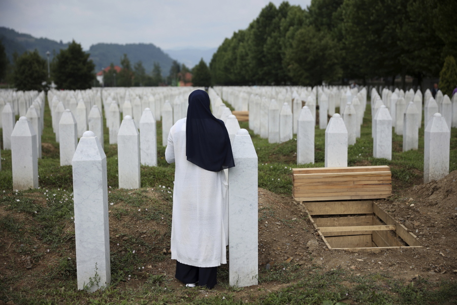 A woman prays near a grave of a family member in the Memorial centre in Potocari, Bosnia, Friday, July 8, 2022. After surviving the 1995 Srebrenica massacre in which over 8,000 of their male relatives were killed, women from the small town in eastern Bosnia dedicated the remaining years of their lives to the re-telling of their trauma to the World, honoring the victims and bringing those responsible for the killings to justice.