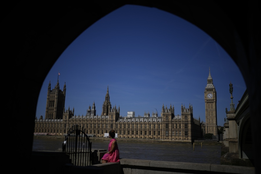 A woman poses for her own phone picture framed by an underpass arch on the south bank of the River Thames backdropped by the Elizabeth Tower, known as Big Ben, and the Houses of Parliament, in London, Monday, July 11, 2022. Candidates to replace Boris Johnson as Britain's prime minister are scattering tax-cutting promises to their Conservative Party electorate, as party officials prepare Monday to quickly narrow the crowded field of more than ten candidates.