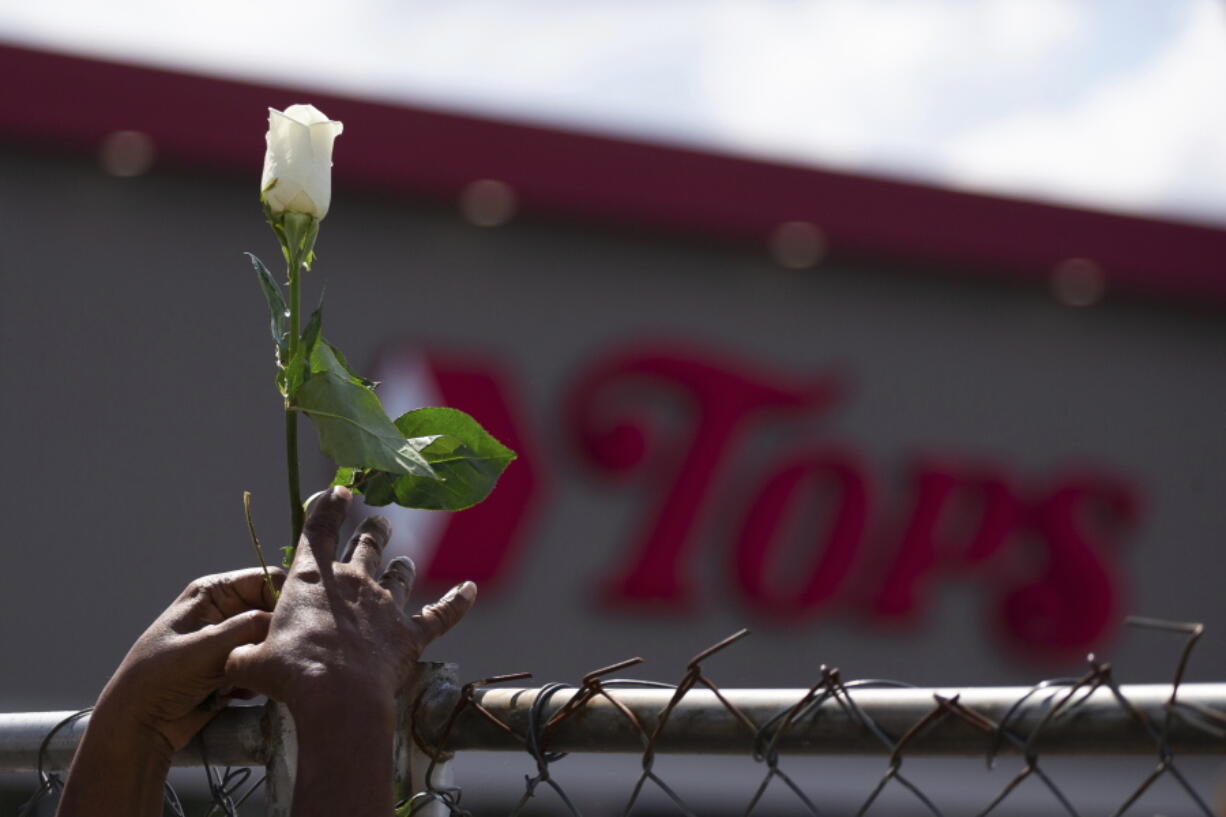 Cariol Horne, 54, places a rose on the fence outside the Tops Friendly Market on Thursday, July 14, 2022, in Buffalo, N.Y. The Buffalo supermarket where 10 Black people were killed by a white gunman is set to reopen its doors, two months after the racist attack.