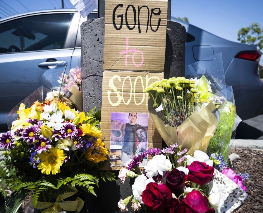 FILE - Flowers, candles and cards have been left at the parking lot of the 7-Eleven store on W. Lambert Road in Brea, Calif., Thursday, July 14, 2022. Authorities said Friday, July 15, 2022, that a suspect has been arrested in a series of deadly robberies at Southern California 7-Eleven convenience stores.