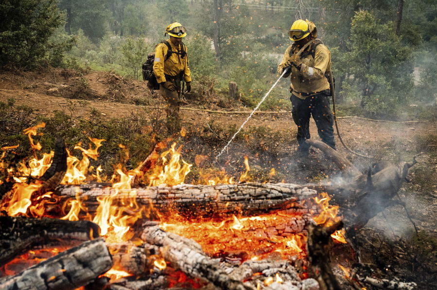Firefighters mop up hot spots while battling the Oak Fire in the Jerseydale community of Mariposa County, Calif., on Monday, July 25, 2022. They are part of Task Force Rattlesnake, a program comprised of Cal Fire and California National Guard firefighters.