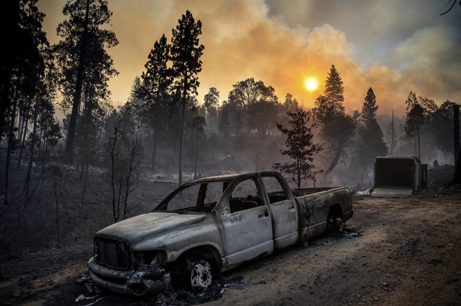 The Oak Fire burns behind a scorched pickup truck in the Jerseydale community of Mariposa County, Calif., early Sunday, July 24, 2022.