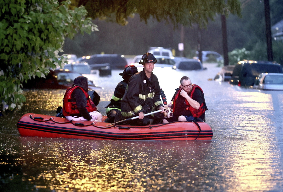 Steven Bertke and his dog Roscoe are taken to dry land by St. Louis firefighters who used a boat to rescue people from their flooded homes on Hermitage Avenue in St. Louis on Tuesday, July 26, 2022. (David Carson/St.