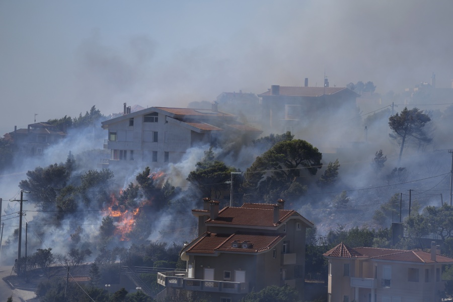 Fire burns next to houses in the area of Drafi east of Athens on Wednesday, July 20, 2022. Hundreds of people were evacuated from their homes late Tuesday as a wildfire threatened mountainside suburbs northeast of Athens. Firefighters battled through the night, struggling to contain the blaze which was being intensified by strong gusts of wind.