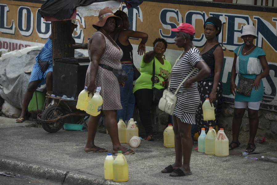 Women show their discomfort as they are being photographed selling contraband gasoline in plastic gallons jugs on a street in Port-au-Prince, Haiti, Thursday, July 14, 2022.