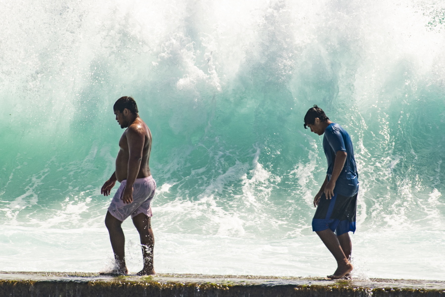 People walk in front of the high surf near Kapahulu Groin (Waikiki Wall) in Waikiki, Hawaii, Sunday, July 17, 2022. (Craig T.