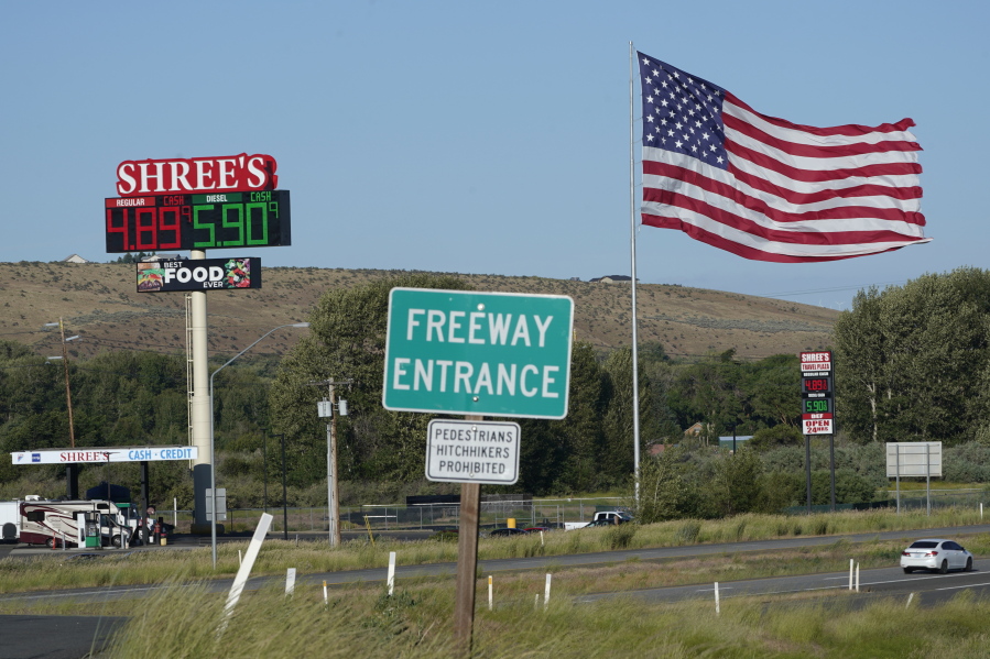 A large U.S. flag flies near a gas station in Thorp, Wash., about 100 miles east of Seattle, Sunday, July 3, 2022. The Fourth of July holiday weekend is congesting highways, even with the national average price for gasoline hovering around $5 per gallon. (AP Photo/Ted S.