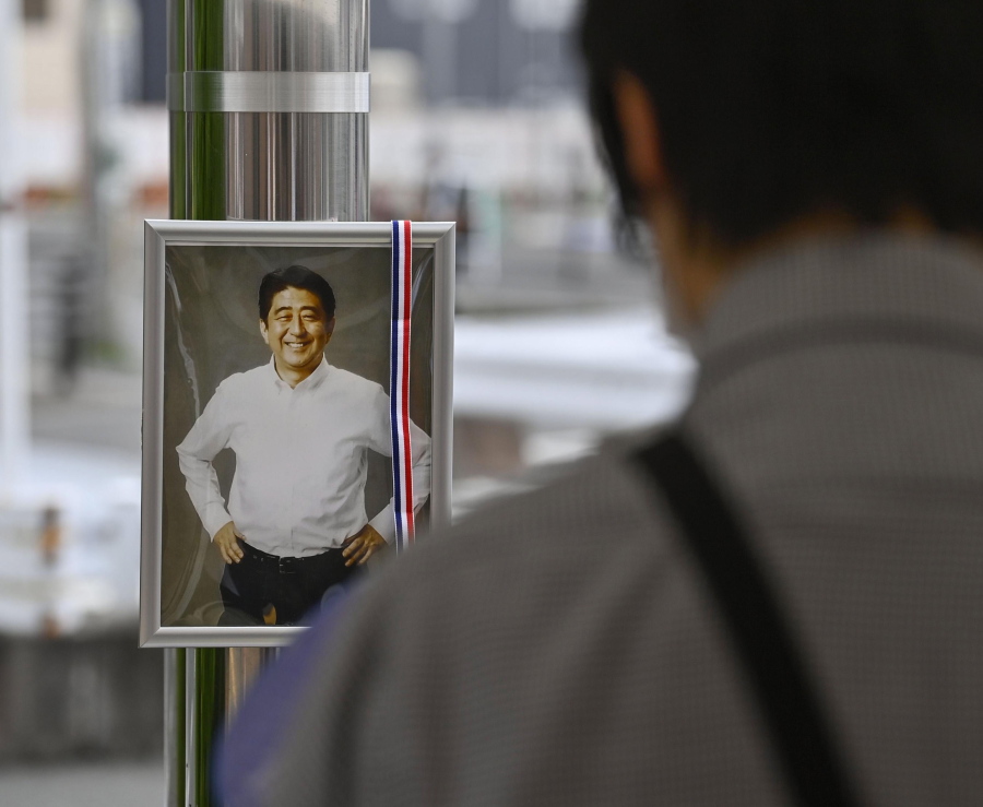 A photo of former Japanese Prime Minister Shinzo Abe is displayed at a memorial area near the site where Abe was fatally shot in Nara, western Japan Friday, July 15, 2022. Many people mourned the death of Abe at the site where he was gunned down during a campaign speech a week ago Friday, shocking a nation known for its low crime rate and strict gun control.