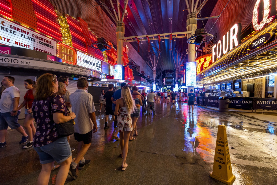 People navigate the rainy walkways as some power is out at the Fremont Street Experience as a powerful storm moves through the area on Thursday, July 28, 2022, in Las Vegas. (L.E.