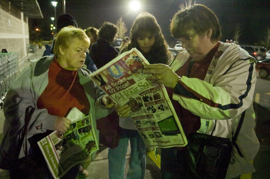 Judi Church, left, Susie Weisel and Judi's sister Tracy Manlow, right, double check the Fred Meyer newspaper insert as they wait in line before dawn on Black Friday in November 2017.