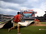 The scoreboard warns of inclement weather in the area as the Washington Nationals grounds crew rolls out the tarp on the field before a baseball game between the Nationals and the Seattle Mariners, Tuesday, July 12, 2022, in Washington.