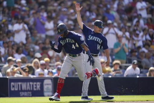 Seattle Mariners' Julio Rodriguez, left, reacts with third base coach Manny Acta after hitting a two-run home run during the fourth inning of a baseball game against the San Diego Padres, Monday, July 4, 2022, in San Diego.