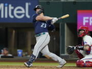 Seattle Mariners' Ty France follows through on a two-run single next to Texas Rangers catcher Jonah Heim during the eighth inning of a baseball game Thursday, July 14, 2022, in Arlington, Texas.
