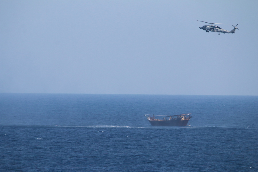 FILE - A U.S. Navy Seahawk helicopter flies over a stateless dhow later found to be carrying a hidden arms shipment in the Arabian Sea, May 6, 2021. The U.S. Navy's Mideast-based 5th Fleet will begin Tuesday, July 5, 2022, to offer rewards for information that could help sailors intercept weapons, drugs and other illicit shipments across the region. The program launches against the backdrop of tensions over Iran's nuclear program and Tehran's arming of Yemen's Houthi rebels. (U.S.