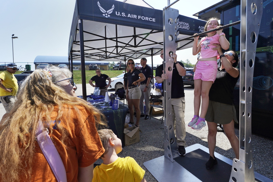 Aubrey White, 10, is helped while hanging on a chin-up bar Sunday at the U.S. Air Force recruiting tent prior to a NASCAR race at the New Hampshire Motor Speedway in Loudon, N.H.
