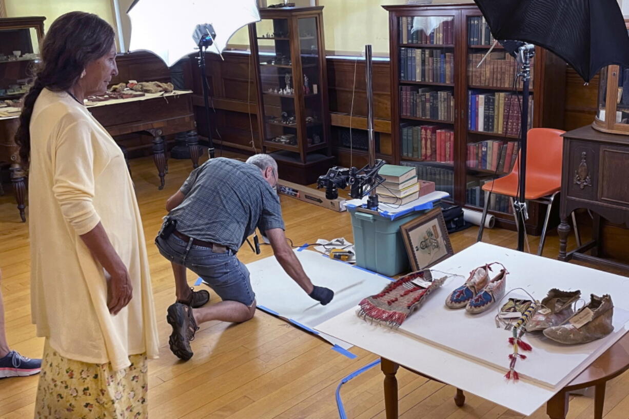 Leola One Feather, left, of the Oglala Sioux Tribe in South Dakota, observes as John Willis photographs Native American artifacts on July 19, 2022, at the Founders Museum in Barre, Massachusetts. The private museum, which is housed in the town library, is working to repatriate as many as 200 items believed to have been taken from Native Americans massacred by U.S. soldiers at Wounded Knee Creek in 1890. Willis is photographing the items for documentation, ahead of their expected return to the tribe.