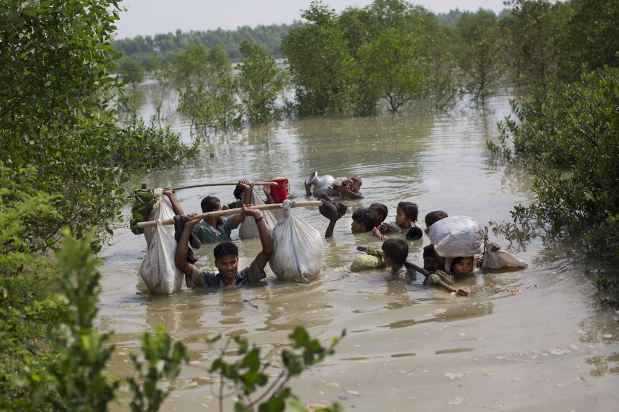 FILE- A Rohingya family reaches the Bangladesh border, Tuesday, Sept. 5, 2017, after crossing a creek of the Naf river on the border with Myanmmar, in Cox's Bazar's Teknaf area. Judges at the International Court of Justice rule Friday July 22, 2022, on whether a case brought by Gambia alleging that Myanmar is committing genocide against the Rohingya can go ahead. Myanmar argues that the court does not have jurisdiction.