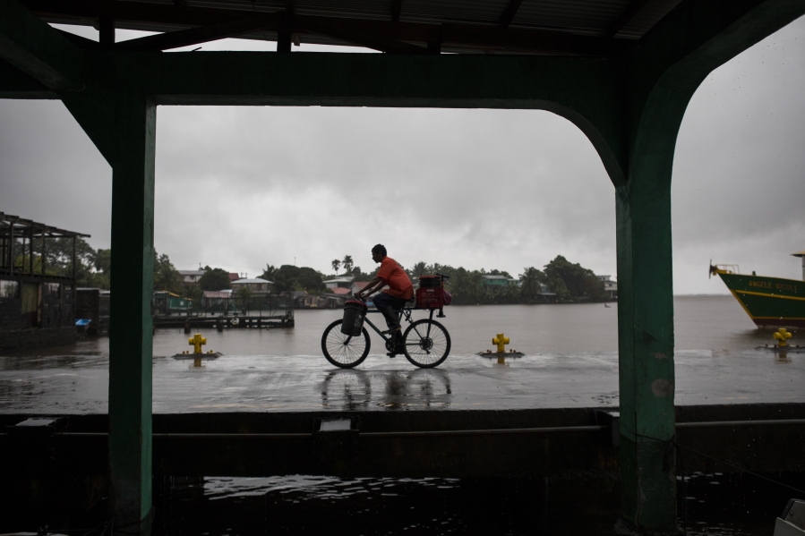 A man rides his bicycle in the rain brought by Tropical Storm Bonnie in Bluefields, Nicaragua, Friday, July 1, 2022. Tropical Storm Bonnie has formed over the Caribbean as it heads for a quick march across Central America and potential development into a hurricane after reemerging in the Pacific.