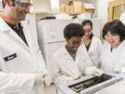 This photo provided by UMBC, University of Maryland, Baltimore County (UMBC) Professor Weihong Lin, second from left, works with students in her biological sciences lab.