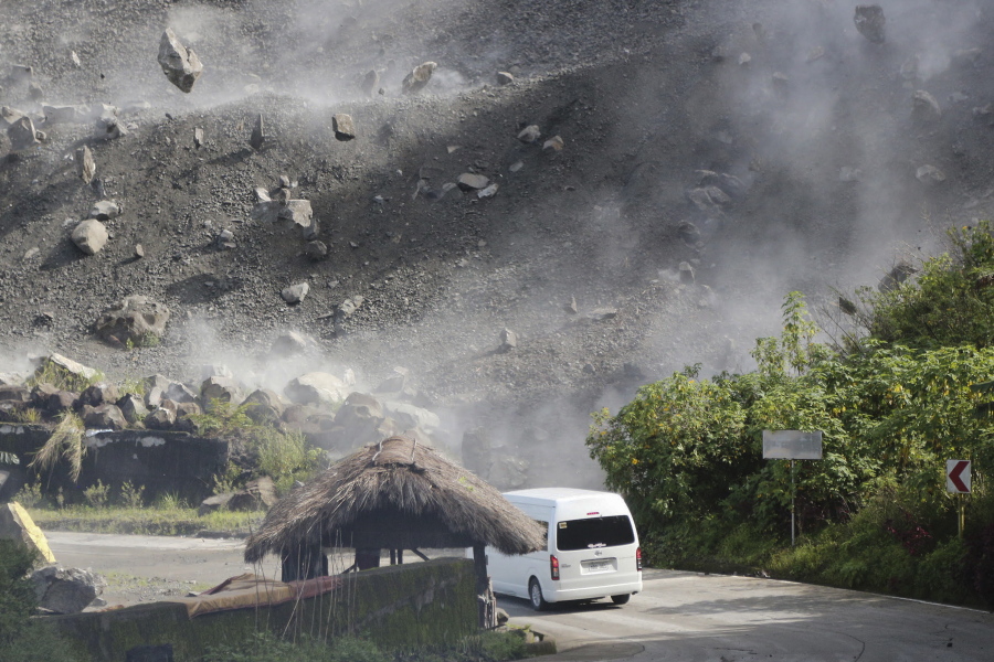 Boulders fall as a vehicle negotiates a road during an earthquake in Bauko, Mountain Province, Philippines on Wednesday July 27, 2022. A strong earthquake left some people dead and injured dozens in the northern Philippines on Wednesday, where the temblor set off small landslides and damaged buildings and churches and prompted terrified crowds and hospital patients in the capital to rush outdoors. One passenger was injured after a boulder hit the vehicle.