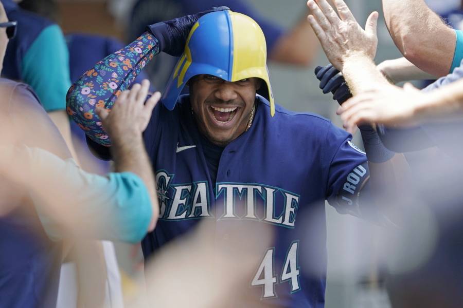Seattle Mariners' Julio Rodriguez wears a helmet as he is greeted in the dugout after his three-run home run against the Texas Rangers during the seventh inning of a baseball game Wednesday, July 27, 2022, in Seattle. (AP Photo/Ted S.
