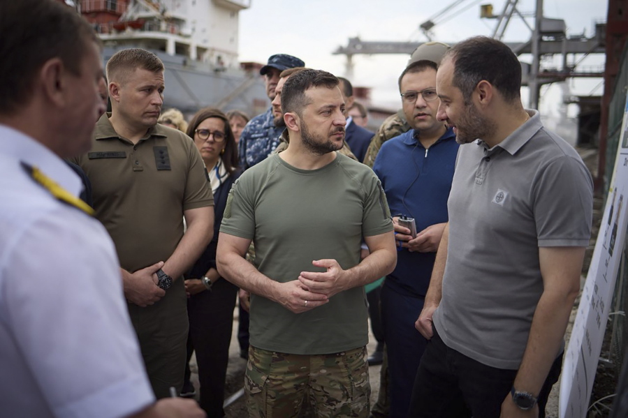 In this photo provided by the Ukrainian Presidential Press Office, Ukrainian President Volodymyr Zelenskyy, center, surrounded by ambassadors of different countries and UN officials, visits a port in Chornomork during loading of grain on a Turkish ship, background, close to Odesa, Ukraine, Friday, July 29, 2022.