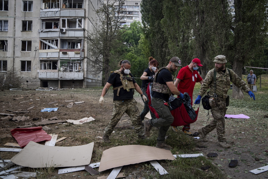 Paramedics carry the body of a woman who was killed during a Russian bombardment at a residential neighborhood in Kharkiv, Ukraine, on Thursday, July 7, 2022.