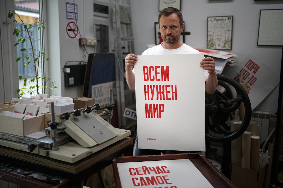 Sergei Besov, a Moscow-based print artist poses for a photo holding a poster reads "Everyone needs peace" in his workshop in Moscow, Russia, Tuesday, July 5, 2022. Besov felt he couldn't stay silent after Russia sent its troops into Ukraine and started printing posters about it. Despite a massive government crackdown on such acts of protest, some Russians have persisted in speaking out against the invasion -- even in the simplest of ways.