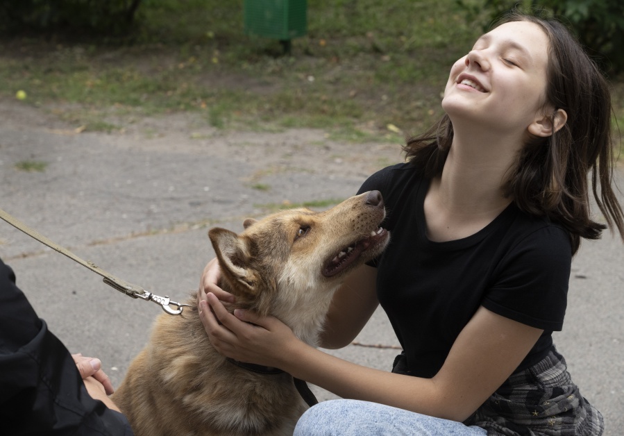 A girl plays with a dog in a pet shelter in Kyiv, Ukraine, Tuesday, July 19, 2022. Shellshocked family pets started roaming around Ukraine's capital with nowhere to go in the opening stages of Russia's war. Volunteers opened a shelter to take them in and try to find them new homes or at least some human companionship.