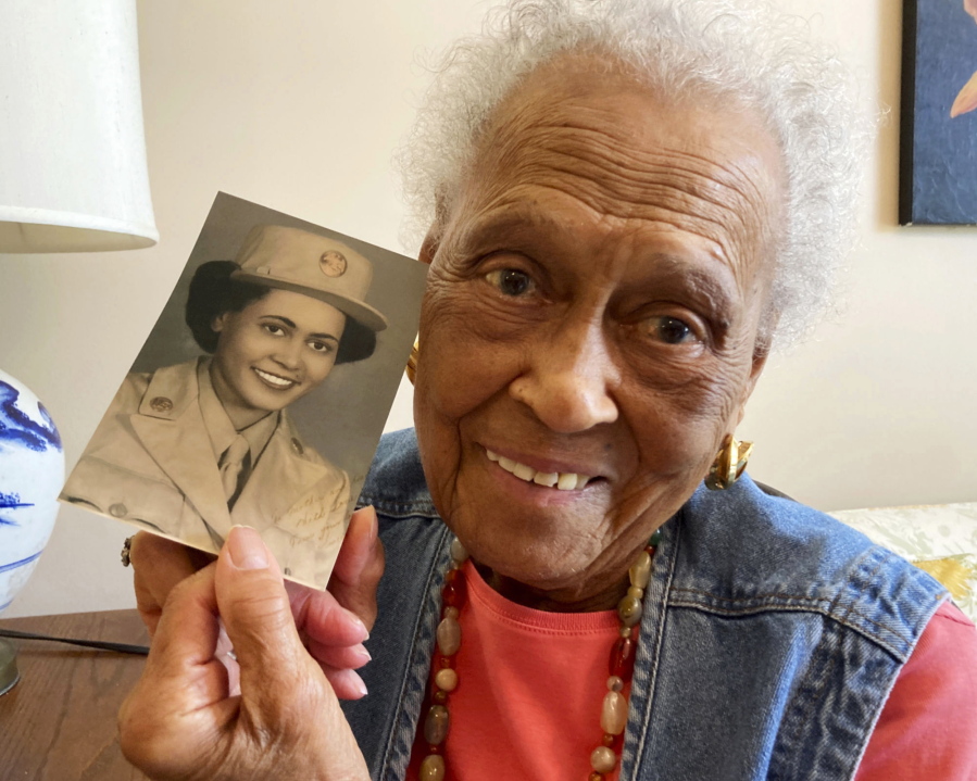 Romay Davis, 102, poses with a photo showing her during World War II, at her home in Montgomery, Ala., Monday, July 25, 2022. Davis is being honored for her service with the all-female, all-Black 6888th Central Postal Directory Battalion, which got mail to U.S. troops in Europe during the war.