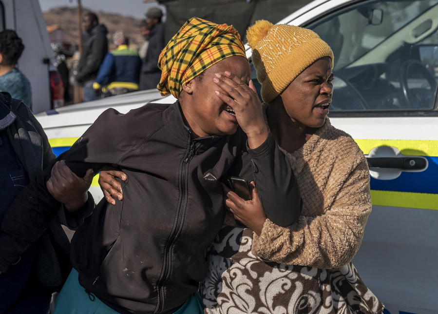 A woman weeps at the scene of an overnight bar shooting in Soweto, South Africa, Sunday July 10, 2022. A mass shooting at a tavern in Johannesburg's Soweto township has killed 15 people and left others in critical condition, according to police.