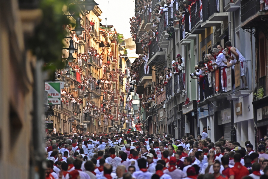 People run through the streets ahead of fighting bulls and steers during the first day of the running of the bulls at the San Fermin Festival in Pamplona, northern Spain, Thursday, July 7, 2022. Revelers from around the world flock to Pamplona every year for nine days of uninterrupted partying in Pamplona's famed running of the bulls festival which was suspended for the past two years because of the coronavirus pandemic.